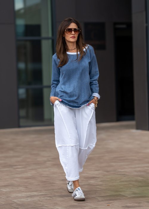 Białe spodnie oversize z obniżonym krokiem i dekoracyjnymi przeszyciami, luźny fason, nowoczesna stylizacja damska.