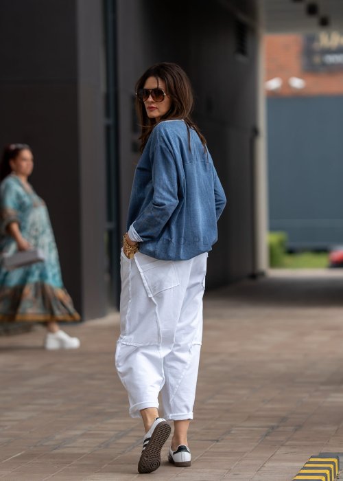 Białe spodnie oversize z obniżonym krokiem i dekoracyjnymi przeszyciami, luźny fason, nowoczesna stylizacja damska.