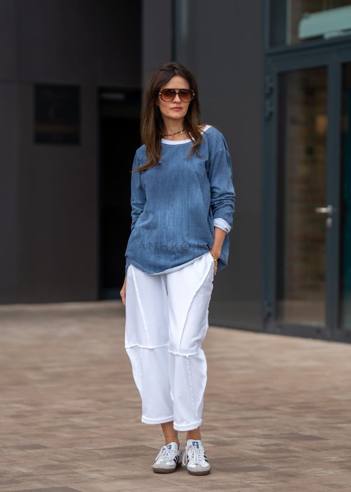 Białe spodnie oversize z obniżonym krokiem i dekoracyjnymi przeszyciami, luźny fason, nowoczesna stylizacja damska.