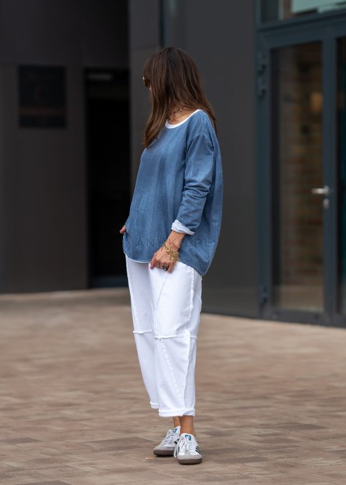 Białe spodnie oversize z obniżonym krokiem i dekoracyjnymi przeszyciami, luźny fason, nowoczesna stylizacja damska.