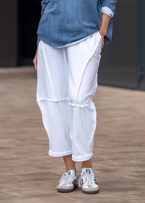 Białe spodnie oversize z obniżonym krokiem i dekoracyjnymi przeszyciami, luźny fason, nowoczesna stylizacja damska.