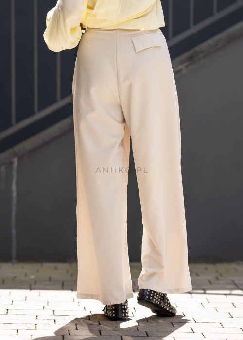 Kremowe spodnie damskie z szeroką nogawką i wysokim stanem, elegancki model z paskiem w talii.