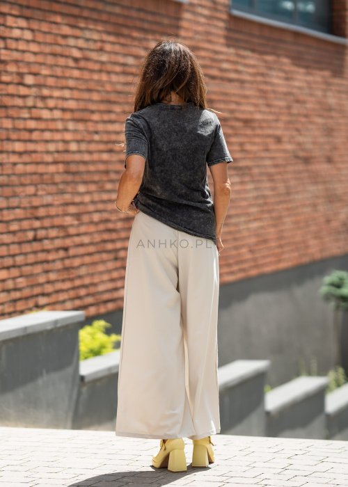 Kremowe spodnie damskie z szeroką nogawką i wysokim stanem, elegancki model z paskiem w talii.