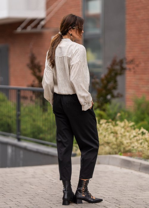 Czarne spodnie damskie typu cygaretki z elastycznym pasem i zwężaną nogawką, zestawione z botkami w eleganckiej miejskiej stylizacji.