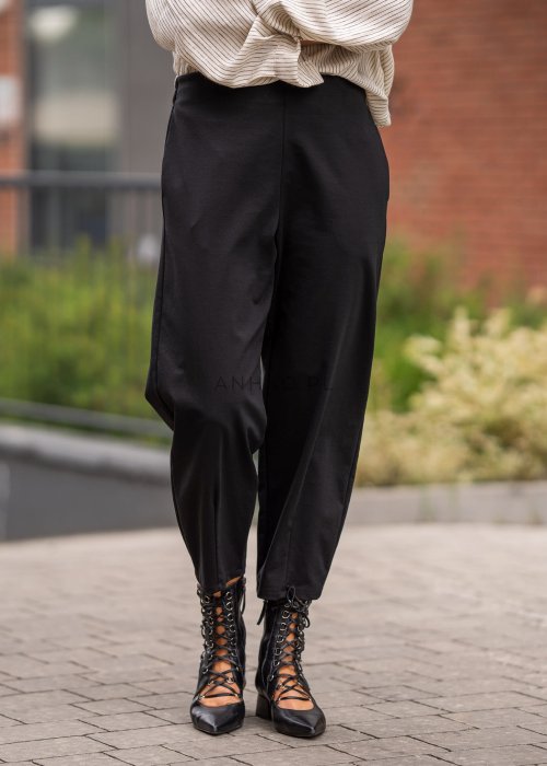 Czarne spodnie damskie typu cygaretki z elastycznym pasem i zwężaną nogawką, zestawione z botkami w eleganckiej miejskiej stylizacji.