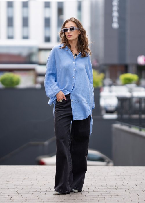 Czarne damskie jeansy z prostą, lekko rozszerzaną nogawką, klasyczny krój z pięcioma kieszeniami i zapięciem na guzik, noszone z białymi sneakersami.