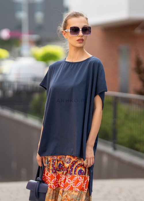 Granatowa bluzka oversize z asymetrycznym dołem i wydłużonym tyłem, zestawiona ze wzorzystą spódnicą. Luźny fason tworzy nowoczesną, miejską stylizację.
