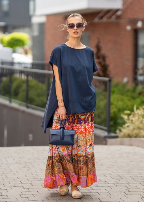 Granatowa bluzka oversize z asymetrycznym dołem i wydłużonym tyłem, zestawiona ze wzorzystą spódnicą. Luźny fason tworzy nowoczesną, miejską stylizację.