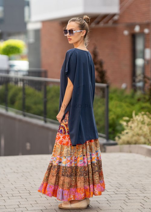 Granatowa bluzka oversize z asymetrycznym dołem i wydłużonym tyłem, zestawiona ze wzorzystą spódnicą. Luźny fason tworzy nowoczesną, miejską stylizację.