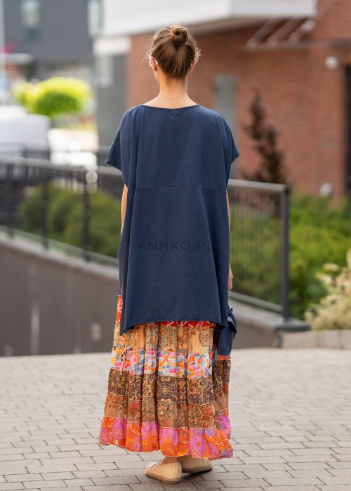 Granatowa bluzka oversize z asymetrycznym dołem i wydłużonym tyłem, zestawiona ze wzorzystą spódnicą. Luźny fason tworzy nowoczesną, miejską stylizację.