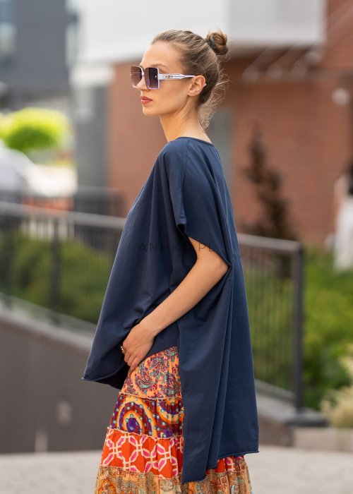 Granatowa bluzka oversize z asymetrycznym dołem i wydłużonym tyłem, zestawiona ze wzorzystą spódnicą. Luźny fason tworzy nowoczesną, miejską stylizację.