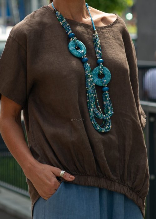 Brązowa bluzka lniana oversize z krótkim rękawem i ściągaczem na dole, stylizowana z szerokimi spodniami i biżuterią w miejskim stylu.