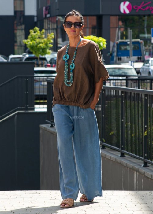 Brązowa bluzka lniana oversize z krótkim rękawem i ściągaczem na dole, stylizowana z szerokimi spodniami i biżuterią w miejskim stylu.