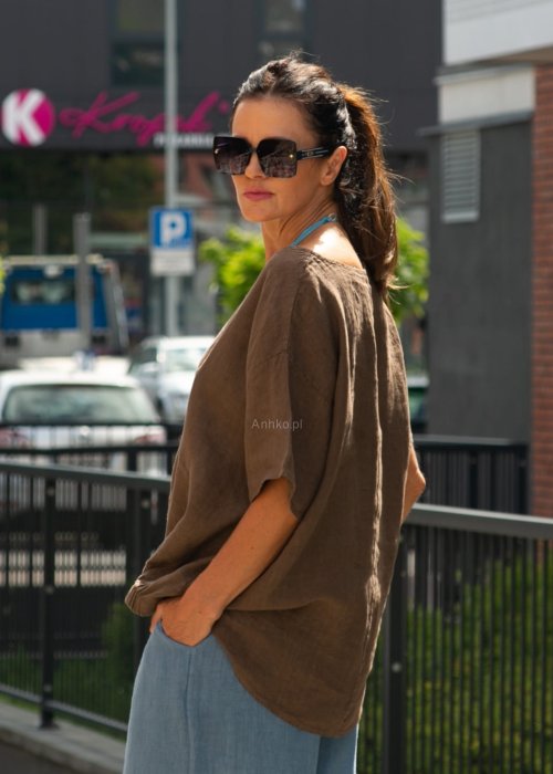 Brązowa bluzka lniana oversize z krótkim rękawem i ściągaczem na dole, stylizowana z szerokimi spodniami i biżuterią w miejskim stylu.