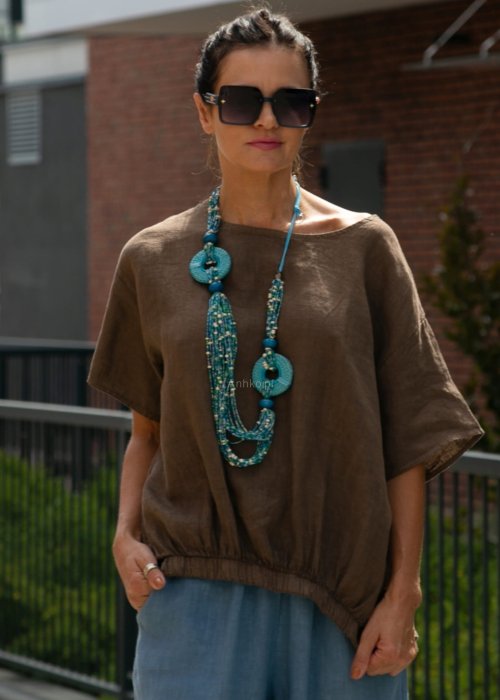 Brązowa bluzka lniana oversize z krótkim rękawem i ściągaczem na dole, stylizowana z szerokimi spodniami i biżuterią w miejskim stylu.