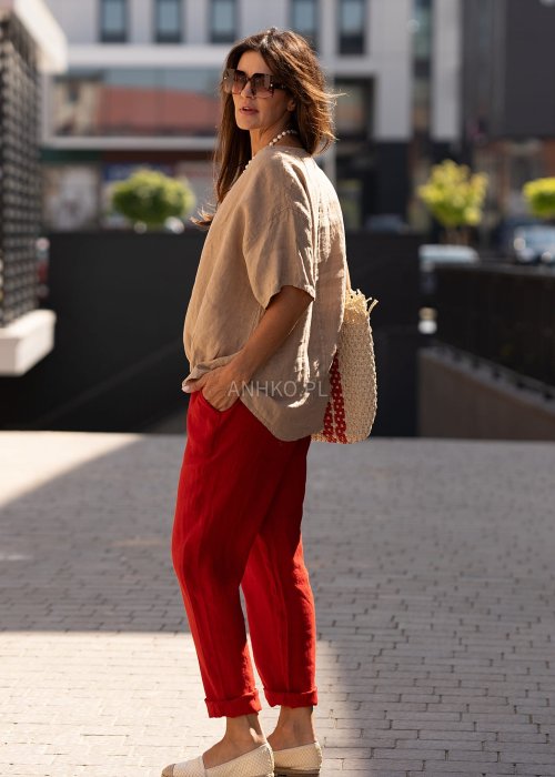 Beżowa bluzka damska oversize z krótkim rękawem i marszczeniem na dole, stylizowana z czerwonymi spodniami w miejskim looku.