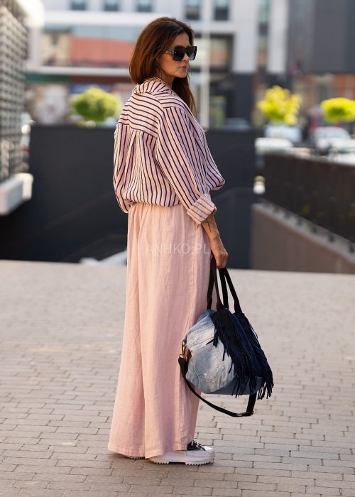 Lniana koszula damska w różowym kolorze z granatowymi paskami, luźny fason z kołnierzykiem i guzikami, stylizacja z jasnymi spodniami.