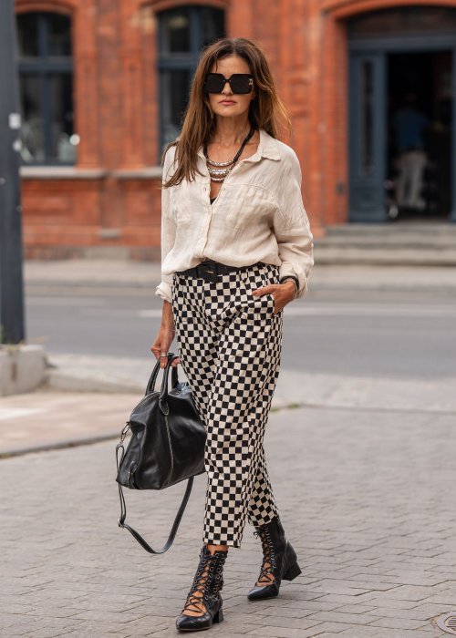 Spodnie damskie w czarno-beżową szachownicę o luźnym kroju z elastycznym pasem i kieszeniami, stylizowane w miejskim looku z koszulą i botkami.
