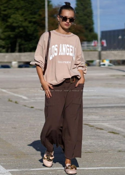 Brązowe spódnico-spodnie damskie o szerokim kroju z wysokim stanem i dużymi kieszeniami, stylizowane z luźną bluzą i mokasynami w miejskim looku.