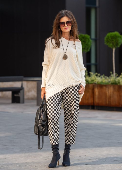 Spodnie damskie w czarno-beżową szachownicę o luźnym kroju z elastycznym pasem i kieszeniami, stylizowane w miejskim looku z koszulą i botkami.