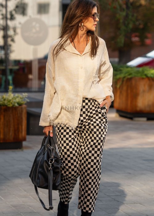 Spodnie damskie w czarno-beżową szachownicę o luźnym kroju z elastycznym pasem i kieszeniami, stylizowane w miejskim looku z koszulą i botkami.