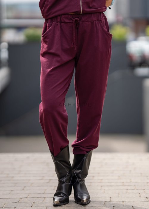 Damski dres w kolorze bordowym z bluzą na zamek i spodniami z elastycznym pasem, stylizacja miejska z botkami.