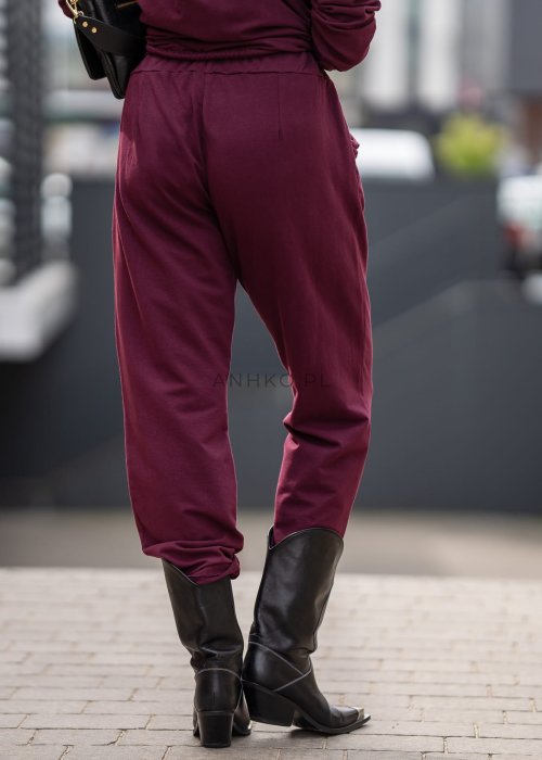 Damski dres w kolorze bordowym z bluzą na zamek i spodniami z elastycznym pasem, stylizacja miejska z botkami.