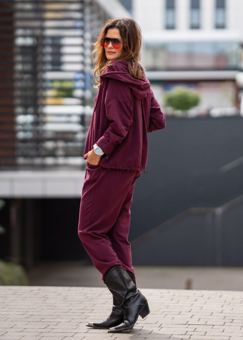 Damski dres w kolorze bordowym z bluzą na zamek i spodniami z elastycznym pasem, stylizacja miejska z botkami.