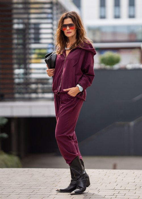 Damski dres w kolorze bordowym z bluzą na zamek i spodniami z elastycznym pasem, stylizacja miejska z botkami.