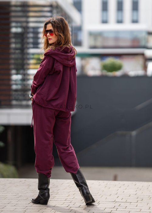 Damski dres w kolorze bordowym z bluzą na zamek i spodniami z elastycznym pasem, stylizacja miejska z botkami.