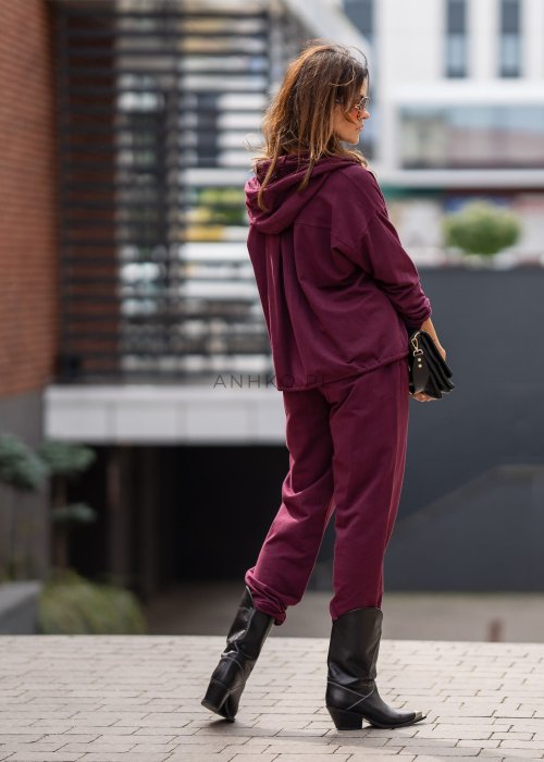 Damski dres w kolorze bordowym z bluzą na zamek i spodniami z elastycznym pasem, stylizacja miejska z botkami.