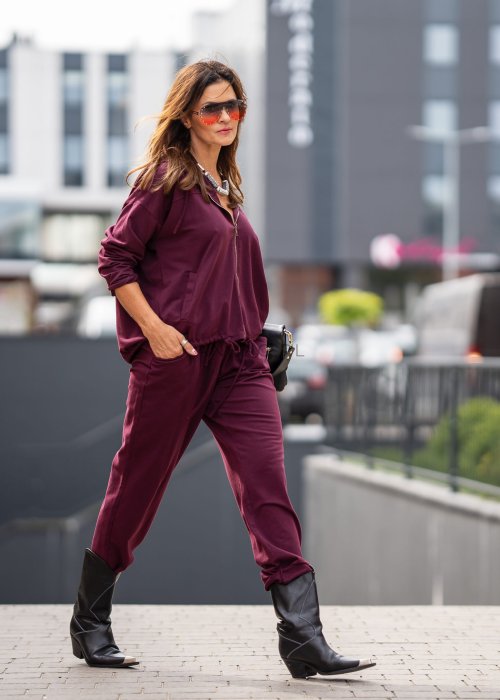 Damski dres w kolorze bordowym z bluzą na zamek i spodniami z elastycznym pasem, stylizacja miejska z botkami.
