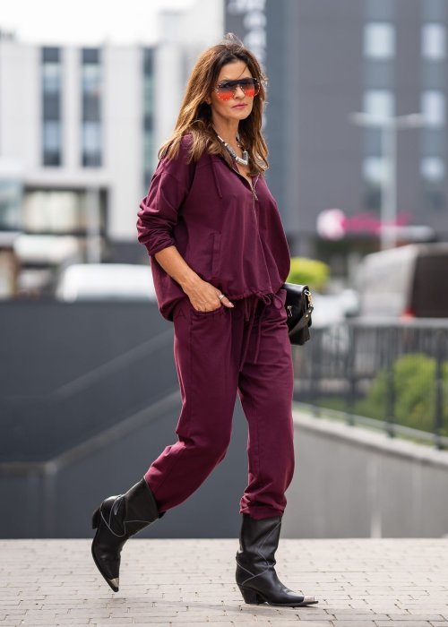 Damski dres w kolorze bordowym z bluzą na zamek i spodniami z elastycznym pasem, stylizacja miejska z botkami.