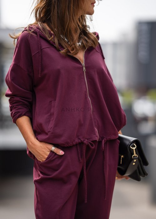 Damski dres w kolorze bordowym z bluzą na zamek i spodniami z elastycznym pasem, stylizacja miejska z botkami.