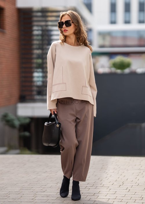 Eleganckie spodnie damskie typu cygaretki w kolorze taupe z elastycznym pasem i zwężaną nogawką, zestawione z botkami na obcasie w miejskiej stylizacji.