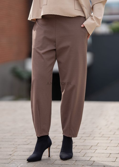 Eleganckie spodnie damskie typu cygaretki w kolorze taupe z elastycznym pasem i zwężaną nogawką, zestawione z botkami na obcasie w miejskiej stylizacji.