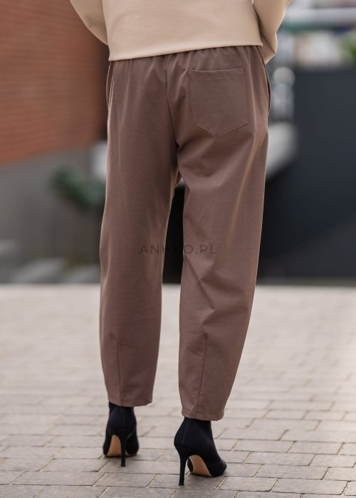 Eleganckie spodnie damskie typu cygaretki w kolorze taupe z elastycznym pasem i zwężaną nogawką, zestawione z botkami na obcasie w miejskiej stylizacji.