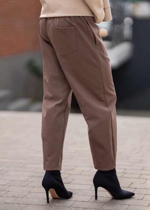 Eleganckie spodnie damskie typu cygaretki w kolorze taupe z elastycznym pasem i zwężaną nogawką, zestawione z botkami na obcasie w miejskiej stylizacji.