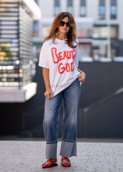 Biały T-shirt damski o luźnym kroju z krótkim rękawem i dużym nadrukiem „Beauty God” w neonowym różowym kolorze.