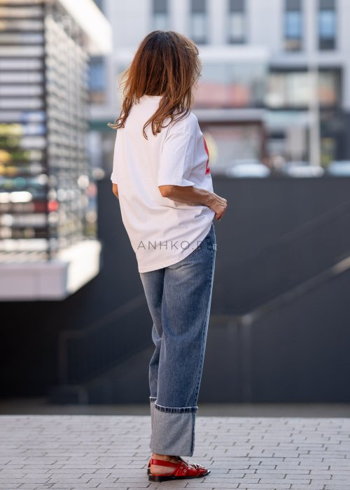 Biały T-shirt damski o luźnym kroju z krótkim rękawem i dużym nadrukiem „Beauty God” w neonowym różowym kolorze.