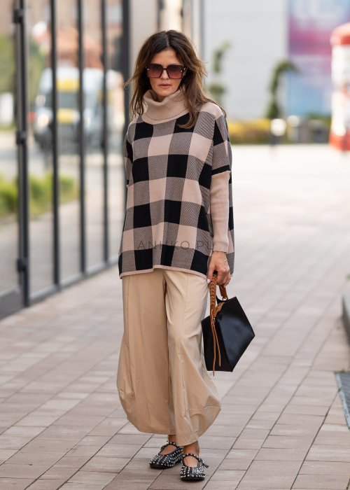 Beżowe spodnie damskie o szerokich nogawkach z efektem bombki i gumką w pasie, zestawione z czarnymi butami z ćwiekami w miejskiej stylizacji.