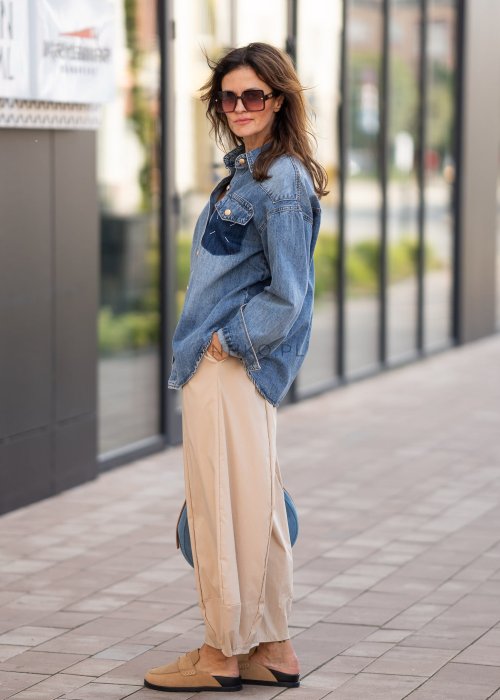 Beżowe spodnie damskie o szerokich nogawkach z efektem bombki i gumką w pasie, zestawione z czarnymi butami z ćwiekami w miejskiej stylizacji.