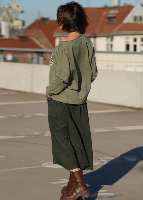 Spódnico-spodnie khaki o długości midi z kieszeniami i elastycznym pasem, stylizowane z botkami i luźną bluzką w miejskim looku.