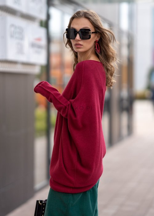 Bordowy sweter oversize o nietoperzowym kroju z dekoltem łódka i asymetrycznym dołem, stylizacja miejska.