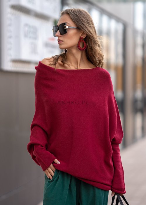 Bordowy sweter oversize o nietoperzowym kroju z dekoltem łódka i asymetrycznym dołem, stylizacja miejska.