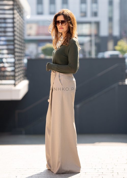 Beżowe spodnie damskie wide leg z wysokim stanem i kopertowym zapięciem, elegancki fason z szerokimi nogawkami w miejskiej stylizacji.