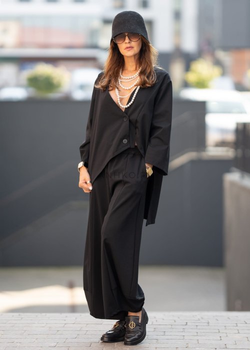 Czarne spodnie damskie o szerokich nogawkach z efektem bombki i elastyczną talią, zestawione z botkami w minimalistycznej stylizacji.