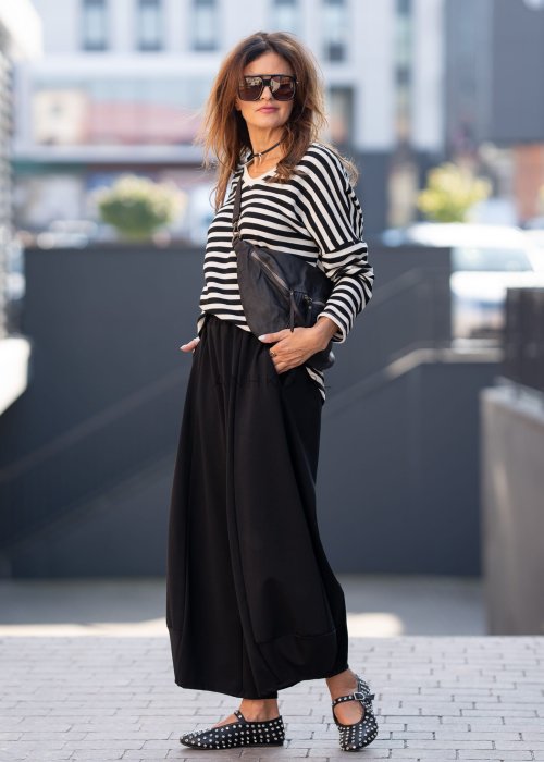 Czarne spodnie damskie o szerokich nogawkach z efektem bombki i elastyczną talią, zestawione z botkami w minimalistycznej stylizacji.