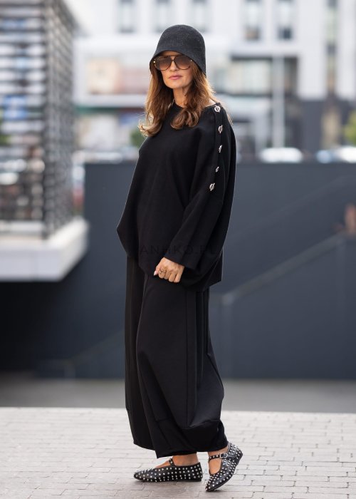 Czarne spodnie damskie o szerokich nogawkach z efektem bombki i elastyczną talią, zestawione z botkami w minimalistycznej stylizacji.