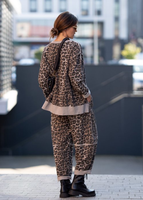 Spodnie damskie w panterkę o kroju oversize z ozdobnymi przeszyciami i elastycznym pasem. Stylizacja z czarnymi botkami w miejskim stylu.